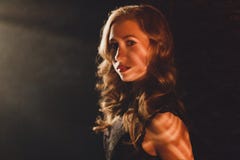 Glamour young woman standing in ray of light and looking in camera royalty free stock photo Glamour young woman standing in ray of light and looking in camera royalty free stock photo