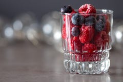 A glass cup on a table filled with frozen raspberry and blueberry berries. royalty free stock image A glass cup on a table filled with frozen raspberry and blueberry berries. royalty free stock image