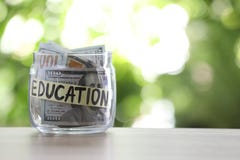 Glass jar with money and label EDUCATION on table against blurred background. royalty free stock images Glass jar with money and label EDUCATION on table against blurred background. royalty free stock images