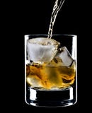Glass Of Whiskey And Ice Under The Pouring Whiskey Royalty Free Stock Images
