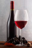 A glass of red wine with grapes and a bottle on a wooden table royalty free stock photo A glass of red wine with grapes and a bottle on a wooden table royalty free stock photo