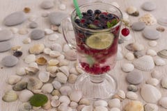 Glass With A Cooling Drink Of Berries And Ice. Misted Glass. Air Bubbles On Glass. A Slice Of Lemon On A Plate On The Background Stock Photography Glass With A Cooling Drink Of Berries And Ice. Misted Glass. Air Bubbles On Glass. A Slice Of Lemon On A Plate On The Background Stock Photography