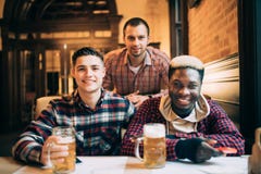 Gli amici multirazziali raggruppano bere e la tostatura della birra al pub Concetto di amicizia con i giovani che godono insieme fotografie stock libere da diritti Gli amici multirazziali raggruppano bere e la tostatura della birra al pub Concetto di amicizia con i giovani che godono insieme fotografie stock libere da diritti
