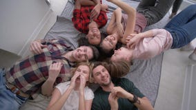 Gli amici si solleticano mentre si trovano sulle loro parti posteriori e ridendo allegro alla macchina fotografica durante il par Gli amici si solleticano mentre si trovano sulle loro parti posteriori e ridendo allegro alla macchina fotografica durante il par
