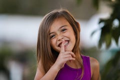 Glimlachend bruin haired meisje die te doen zwijgen vinger gebruiken stock foto Glimlachend bruin haired meisje die te doen zwijgen vinger gebruiken stock foto