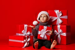 Glimlachend grappig kind in gift van de holdingskerstmis van de Kerstman de rode hoed ter beschikking Kerstmistak en klokken royalty-vrije stock afbeeldingen Glimlachend grappig kind in gift van de holdingskerstmis van de Kerstman de rode hoed ter beschikking Kerstmistak en klokken royalty-vrije stock afbeeldingen