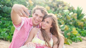 Glimlachend jong paar in liefde die zelfportret met cameratelefoon nemen op strand stock videobeelden Glimlachend jong paar in liefde die zelfportret met cameratelefoon nemen op strand stock videobeelden