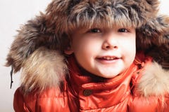 Glimlachend kind in bontkap en oranje de winterjacket.fashion jongen stock fotografie Glimlachend kind in bontkap en oranje de winterjacket.fashion jongen stock fotografie