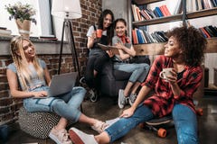 Glimlachende jonge vrouwen die samen met laptop en koffiekoppen zitten royalty-vrije stock foto's Glimlachende jonge vrouwen die samen met laptop en koffiekoppen zitten royalty-vrije stock foto's