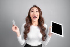 Glimlachende vrouw die lege de tabletpc van de creditcardgreep ter beschikking, over grijze achtergrond tonen royalty-vrije stock foto Glimlachende vrouw die lege de tabletpc van de creditcardgreep ter beschikking, over grijze achtergrond tonen royalty-vrije stock foto