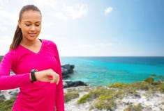Glimlachende vrouw met het horloge van het harttarief op strand royalty-vrije stock foto Glimlachende vrouw met het horloge van het harttarief op strand royalty-vrije stock foto