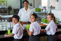 Glimlachende vrouw met schoolkinderen in kantine royalty-vrije stock foto Glimlachende vrouw met schoolkinderen in kantine royalty-vrije stock foto