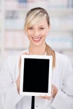 Glimlachende vrouwelijke apotheker die een lege tablet houden stock afbeeldingen Glimlachende vrouwelijke apotheker die een lege tablet houden stock afbeeldingen