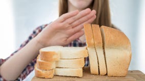 Glutenintoleranzkonzept Junges Mädchen lehnt ab, weißes brea zu essen lizenzfreie stockfotografie Glutenintoleranzkonzept Junges Mädchen lehnt ab, weißes brea zu essen lizenzfreie stockfotografie