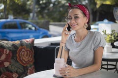 Glücklicher Brunette ist am Handy, der im Straßencafé sitzt, Modell aufwirft mit Telefon lizenzfreies stockbild Glücklicher Brunette ist am Handy, der im Straßencafé sitzt, Modell aufwirft mit Telefon lizenzfreies stockbild
