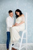 Glückliches Paar mit schwangerer Frau im weißen Kleid auf dem Stuhl stockfotos Glückliches Paar mit schwangerer Frau im weißen Kleid auf dem Stuhl stockfotos