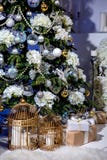 Glänzender Weihnachtsbaum verziert mit Bällen und Blumen, Geschenke und Kerzen in den Käfigen unter ihm im Wohnzimmer Ein Aufbau stockfoto Glänzender Weihnachtsbaum verziert mit Bällen und Blumen, Geschenke und Kerzen in den Käfigen unter ihm im Wohnzimmer Ein Aufbau stockfoto