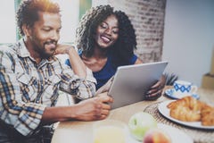 Glückliche Afroamerikanerpaare frühstücken zusammen morgens am Holztisch Lächelnder schwarzer Mann und seiner Lizenzfreies Stockbild Glückliche Afroamerikanerpaare frühstücken zusammen morgens am Holztisch Lächelnder schwarzer Mann und seiner Lizenzfreies Stockbild