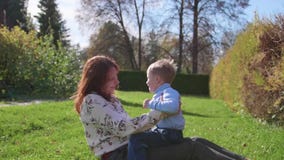 Glückliche Familie, die auf dem Rasen stillsteht Mutter mit Weichheit und Liebe spielt mit ihrem Kind, das Sohnlachen, er hat Spa stock video footage Glückliche Familie, die auf dem Rasen stillsteht Mutter mit Weichheit und Liebe spielt mit ihrem Kind, das Sohnlachen, er hat Spa stock video footage