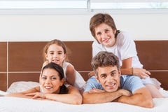 Glückliche Familie, die auf einem Bett liegt stockbilder Glückliche Familie, die auf einem Bett liegt stockbilder