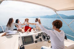 Glückliche Freunde, die Gläser Champagner klirren und auf Yacht segeln lizenzfreie stockbilder Glückliche Freunde, die Gläser Champagner klirren und auf Yacht segeln lizenzfreie stockbilder