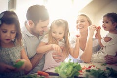 Glückliche junge Familie, die zusammen Salat zubereitet stockbild Glückliche junge Familie, die zusammen Salat zubereitet stockbild