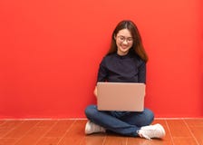 Glückliche junge Frau, die auf dem Boden mit den gekreuzten Beinen sitzt und Laptop auf grauem Hintergrund verwendet stockbilder Glückliche junge Frau, die auf dem Boden mit den gekreuzten Beinen sitzt und Laptop auf grauem Hintergrund verwendet stockbilder