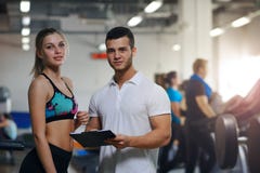Glückliche junge Frau und ihr persönlicher Trainer in der Turnhalle lizenzfreies stockfoto Glückliche junge Frau und ihr persönlicher Trainer in der Turnhalle lizenzfreies stockfoto