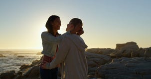 Glückliche junge Paare, die auf einander auf felsigem Ufer 4k einwirken stock video Glückliche junge Paare, die auf einander auf felsigem Ufer 4k einwirken stock video