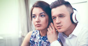 Glückliche junge Paare, die zusammen auf dem Boden sitzen Lizenzfreie Stockfotos Glückliche junge Paare, die zusammen auf dem Boden sitzen Lizenzfreie Stockfotos