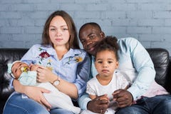 Glückliche multiethnische Familie, die auf dem Sofa im modernen Innenraum sitzt lizenzfreie stockbilder Glückliche multiethnische Familie, die auf dem Sofa im modernen Innenraum sitzt lizenzfreie stockbilder