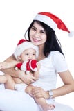Glückliche Mutter und Baby in den roten Weihnachtshüten stockbilder Glückliche Mutter und Baby in den roten Weihnachtshüten stockbilder
