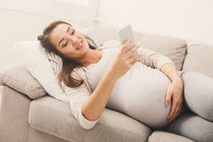 Glückliche schwangere Frau, die Smartphone verwendet stockfotografie Glückliche schwangere Frau, die Smartphone verwendet stockfotografie