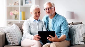 Glückliche ältere Paare mit Tablet-Computer zu Hause stock video footage Glückliche ältere Paare mit Tablet-Computer zu Hause stock video footage