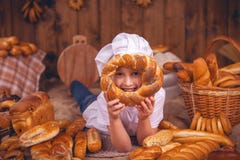Glücklicher Babychef ist ein Bäcker, der viele Brötchen trägt lizenzfreies stockbild Glücklicher Babychef ist ein Bäcker, der viele Brötchen trägt lizenzfreies stockbild
