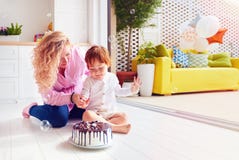 Glücklicher Mutter- und Kleinkindsohn, der Finger im Geburtstagskuchen stößt stockfotografie Glücklicher Mutter- und Kleinkindsohn, der Finger im Geburtstagskuchen stößt stockfotografie