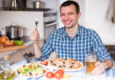 Glücklicher männlicher Abendessenpizzasalat in der Küche stockbilder Glücklicher männlicher Abendessenpizzasalat in der Küche stockbilder