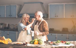 Glücklicher reifer Ehemann und Frau, die geschmackvolle Brötchen mit Tee isst lizenzfreies stockfoto Glücklicher reifer Ehemann und Frau, die geschmackvolle Brötchen mit Tee isst lizenzfreies stockfoto