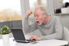 Glücklicher reifer Mann, der eine gute Überraschung auf Laptop hat stockfoto Glücklicher reifer Mann, der eine gute Überraschung auf Laptop hat stockfoto