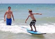 Glücklicher Vater, der seinen jungen Sohn unterrichtet zu surfen Glücklicher Vater, der seinen jungen Sohn unterrichtet zu surfen