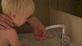 Glücklicher älterer Mann wäscht seine Hände auf Hahn von seiner Hand und von Gesicht zu seinem kleinen Sohn und wischt ihn mit Tu stock footage Glücklicher älterer Mann wäscht seine Hände auf Hahn von seiner Hand und von Gesicht zu seinem kleinen Sohn und wischt ihn mit Tu stock footage