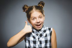 Glückliches Mädchen, das sich thubs zeigt Nahaufnahme-Porträtkinderlächeln lokalisiert auf Grau lizenzfreie stockfotos Glückliches Mädchen, das sich thubs zeigt Nahaufnahme-Porträtkinderlächeln lokalisiert auf Grau lizenzfreie stockfotos