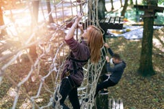 Glückliches Mädchen, Frau, kletternder Gang in einem Abenteuer, Seilstraße, Versicherung, Anziehungskraft, Vergnügungspark, aktiv lizenzfreies stockbild Glückliches Mädchen, Frau, kletternder Gang in einem Abenteuer, Seilstraße, Versicherung, Anziehungskraft, Vergnügungspark, aktiv lizenzfreies stockbild