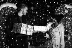 Glückliches Paar mit Geschenkbox über Weihnachtslichtern stockfoto Glückliches Paar mit Geschenkbox über Weihnachtslichtern stockfoto