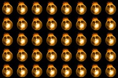 Glühende Lampen auf einem schwarzen Hintergrund Viele Lampen glänzen in Folge mit gelbem Licht Dachbodenkonzept stockfotografie Glühende Lampen auf einem schwarzen Hintergrund Viele Lampen glänzen in Folge mit gelbem Licht Dachbodenkonzept stockfotografie