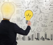 Glühlampe der Geschäftsmannschreibensidee auf Wand stockbild Glühlampe der Geschäftsmannschreibensidee auf Wand stockbild