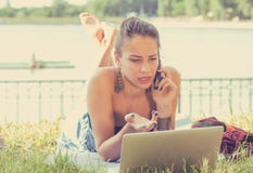 Gniewna kobieta opowiada na telefonie komórkowym pracuje na laptopie outdoors zdjęcie stock Gniewna kobieta opowiada na telefonie komórkowym pracuje na laptopie outdoors zdjęcie stock