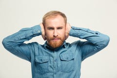 Gniewny sfrustowany brodaty mężczyzna zamykał ucho rękami Obrazy Stock Gniewny sfrustowany brodaty mężczyzna zamykał ucho rękami Obrazy Stock