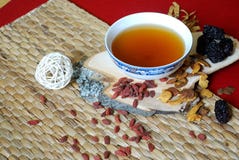 Goji berries, chinese dates, astragalus root pieces with a bowl of herb tea on red background. Side view. stock image Goji berries, chinese dates, astragalus root pieces with a bowl of herb tea on red background. Side view. stock image