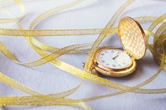 Gold Vintage pocket watch with golden ribbons on grey cement background. Hourglass or sand timer, symbol of time. Selective focus royalty free stock photo Gold Vintage pocket watch with golden ribbons on grey cement background. Hourglass or sand timer, symbol of time. Selective focus royalty free stock photo